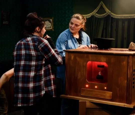 Deux joueuses devant le coffre en bois d’un escape game mobile installé en entreprise