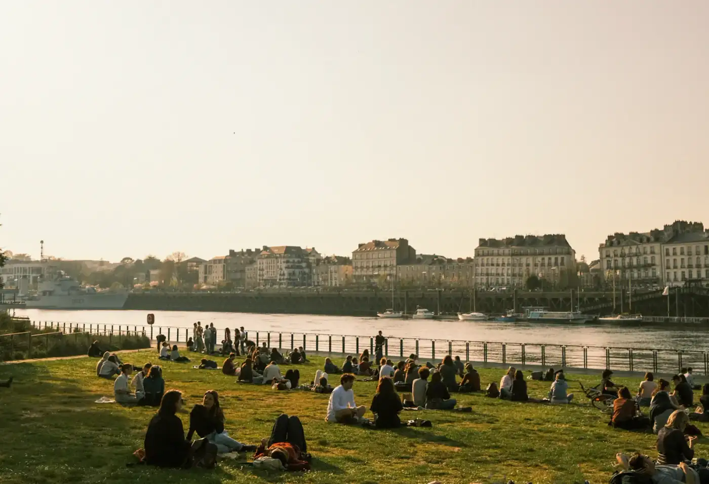 Groupes assis sur une pelouse au bord de la Loire à Nantes, en fin de journée