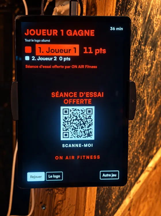La tablette en fin de partie : Joueur 1 gagne, séance d'essai offerte par ON AIR Fitness, avec un QR code à scanner